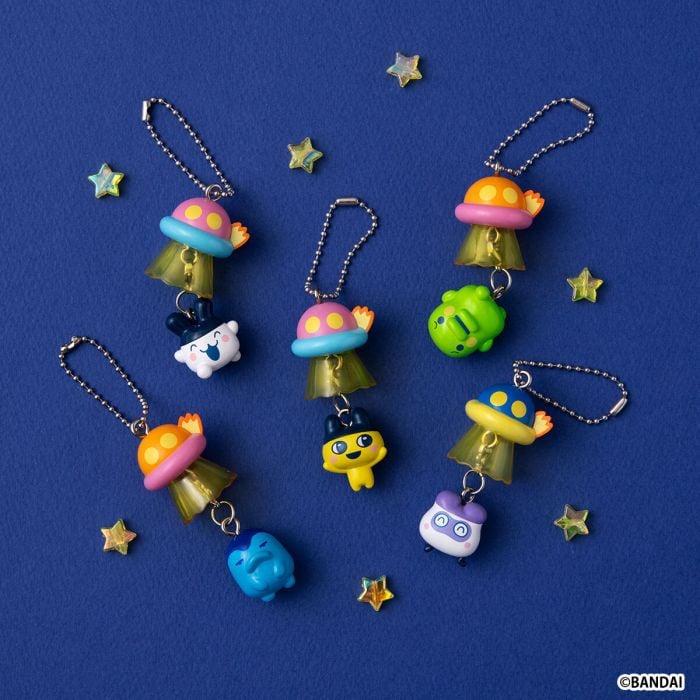 Lineup of 5 Bandai Tamagotchi UFO Swing Gashapon charms including Mametchi, Kuchipatchi, and Mimitchi being abducted by colorful UFOs.