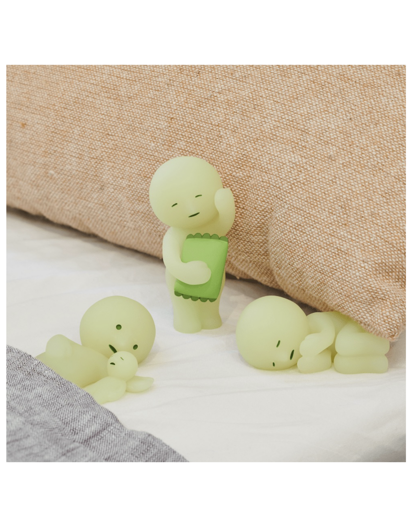 Three small green plush toys on a textured surface