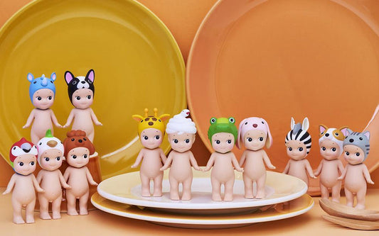 Row of small figurines on a yellow plate with an orange background